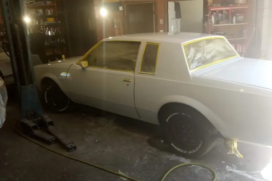 An older coupe in sealer with the glass masked, waiting on color